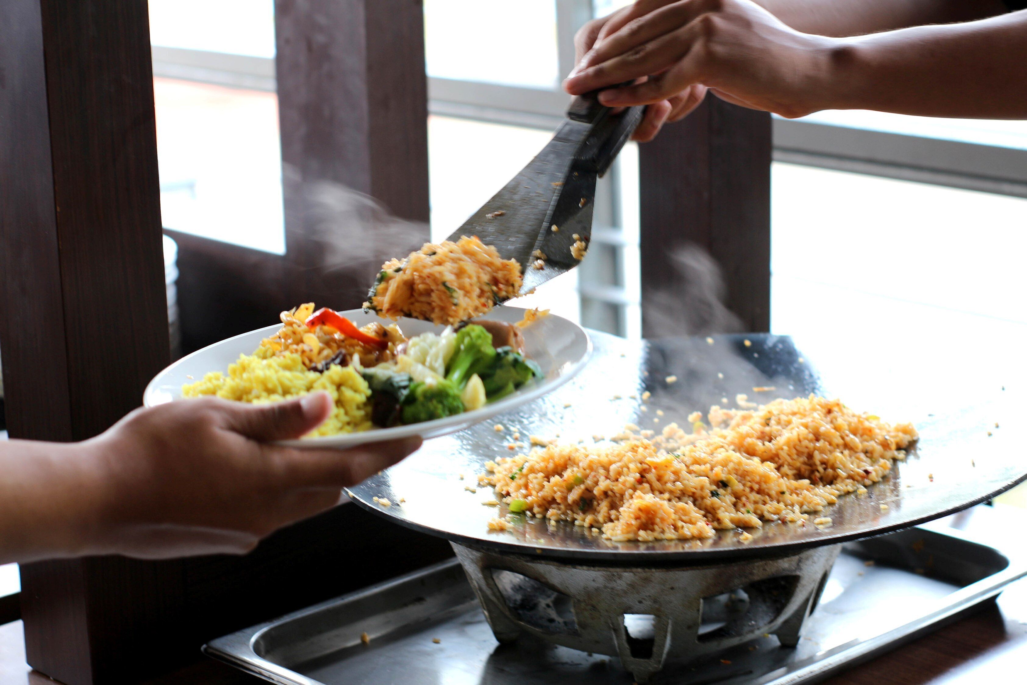 A person serving food from a pan onto a plate.