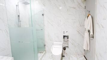 A modern bathroom with a glass-enclosed shower, a toilet, and a towel rack.