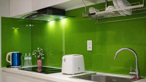 Una cocina moderna con un salpicadero verde, un lavamanos de acero inoxidable, un tostador y una tetera.