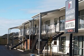 Ein Pegasus Gateway Motel mit mehreren Etagen, Außentreppen und einem Schild.