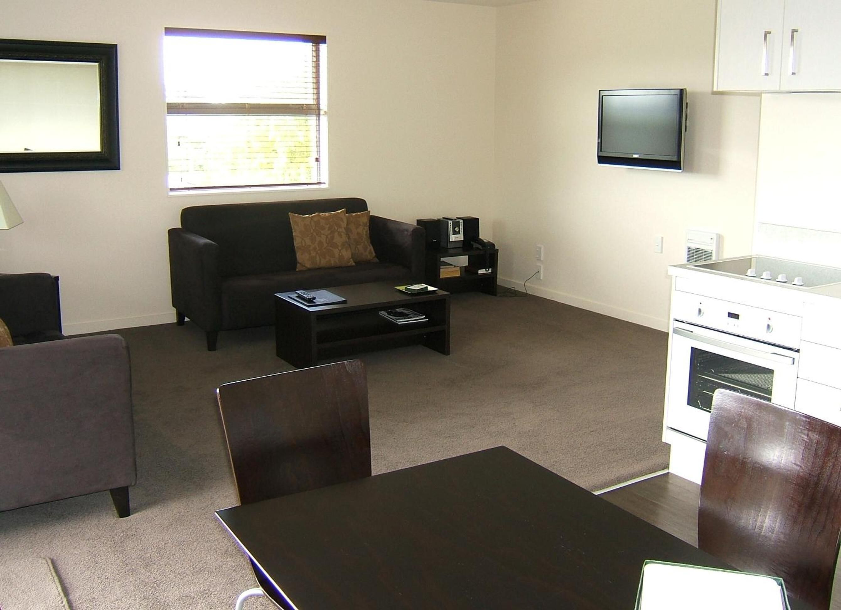 Una sala de estar con sofá, mesa de centro, televisor y kitchenette.