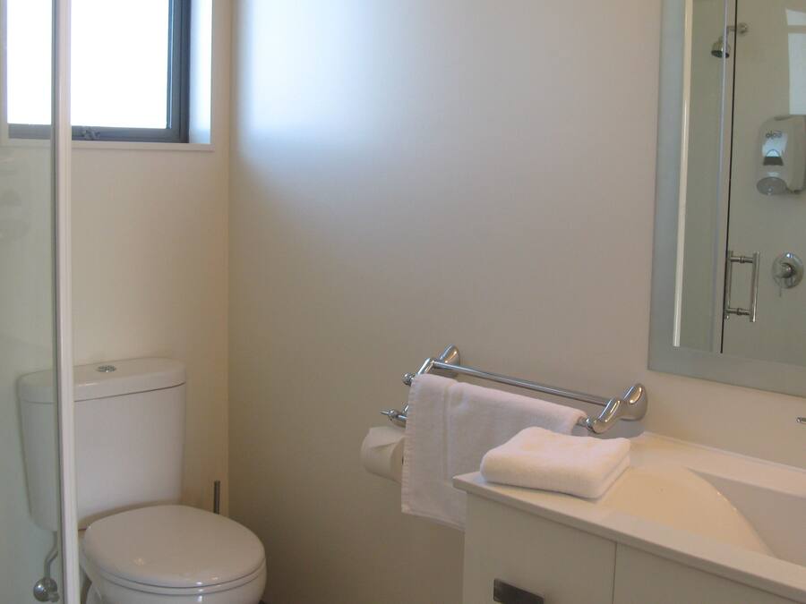 A bathroom with a toilet, sink, and mirror.