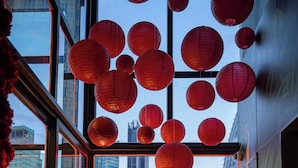 A modern room with a large window, red lanterns, a unique chair, and a view of the cityscape. - Hotel Clover Asoke (Bangkok)
