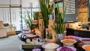 A buffet with various food items and decorative plants. - Hotel Clover Asoke (Bangkok)
