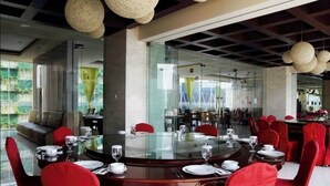 A dining area with round tables, red upholstered chairs, and a glass partition. - Horison Lampung (Bandar Lampung)