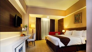 A hotel room with a bed, a desk, a TV, and a window with curtains. - Horison Lampung (Bandar Lampung)