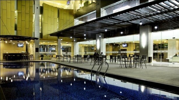 An indoor swimming pool with a clear view of the surrounding area, including seating and a bar. - Horison Lampung (Bandar Lampung)