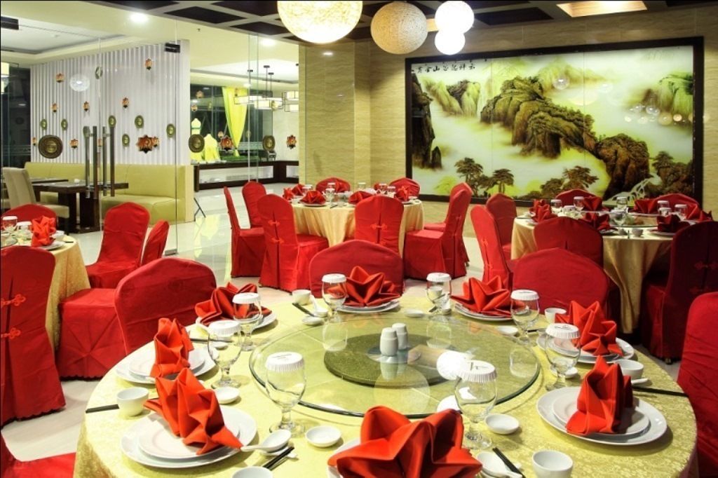 A dining area with round tables set for multiple guests, red chairs, and a large wall mural.