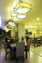 A restaurant with multiple dining tables and chairs, geometric pendant lighting, and a clean, modern interior.