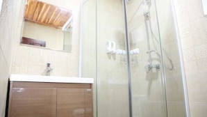 Une salle de bain avec une douche à parois de verre, un meuble-lavabo en bois et un miroir au-dessus du lavabo.