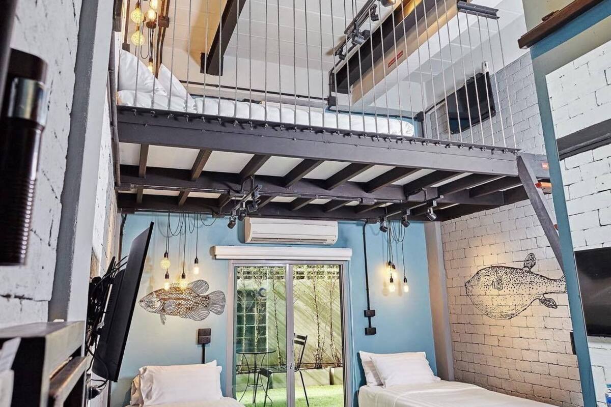 A loft-style bedroom with a bunk bed, a fish mural, and a view of the outdoors.