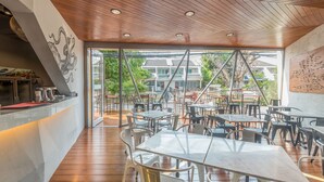 Een terras met houten vloer, metalen tafels en stoelen.