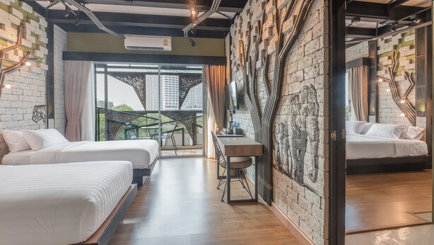 Een moderne hotelkamer met twee bedden, een eettafel en uitzicht op een stadsbeeld.