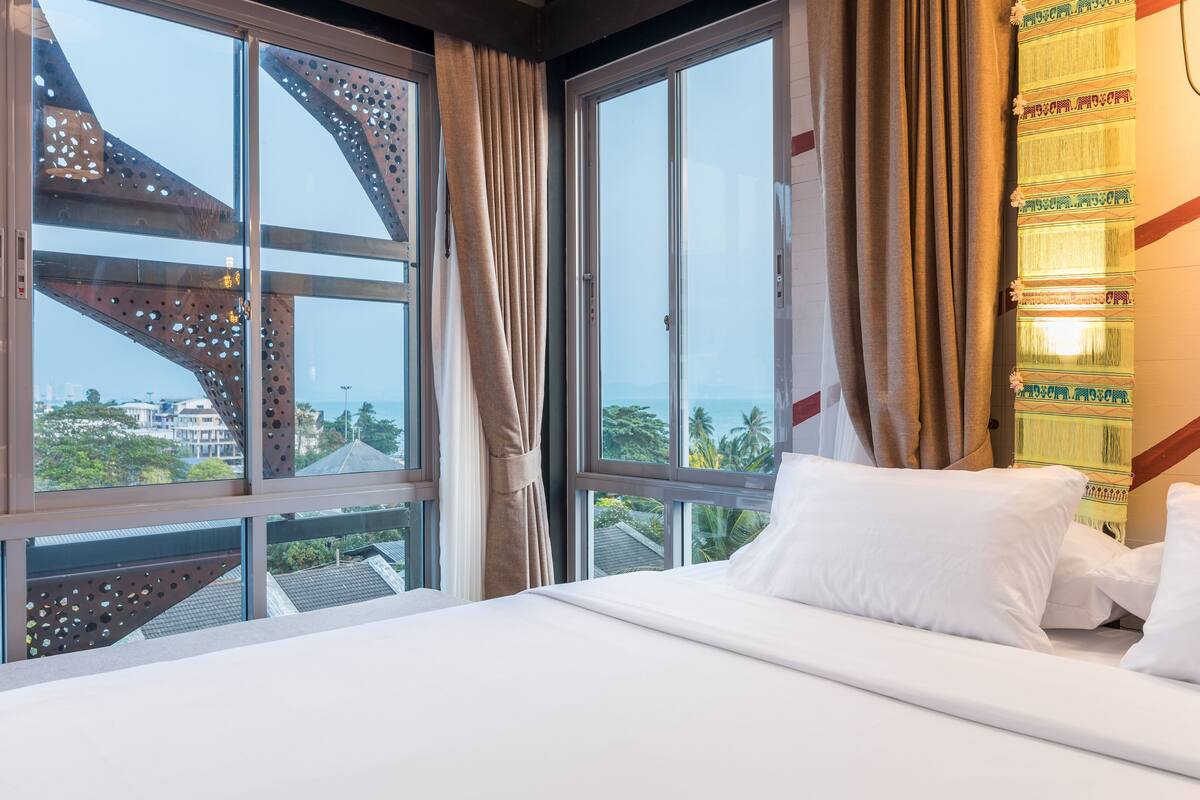 A hotel room with a large bed, two windows, and a view of the cityscape.