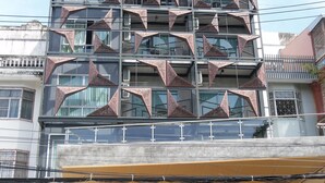 Een meerhoog gebouw met een opvallende geometrische gevel en een overdekt terras.
