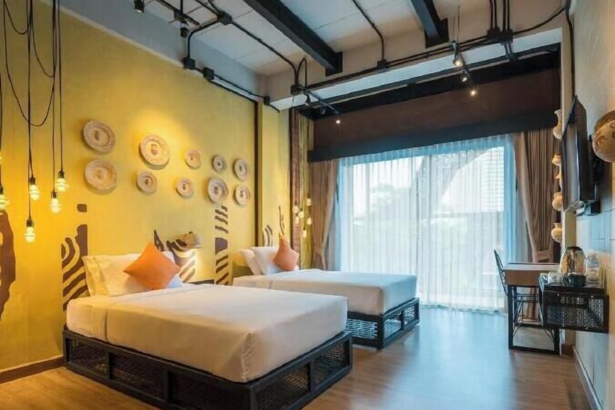 A hotel room with two beds, a dining area, and a large window with curtains.