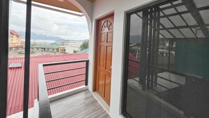 A balcony with a view of buildings and mountains. - Cozy Coron Inn (Coron)
