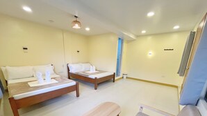 A hotel room with two beds, a small table, and a bench. - Cozy Coron Inn (Coron)