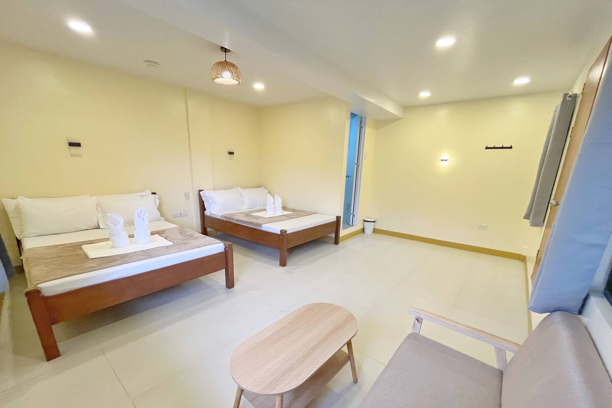 Una habitación de hotel con dos camas, una mesita y un banco.