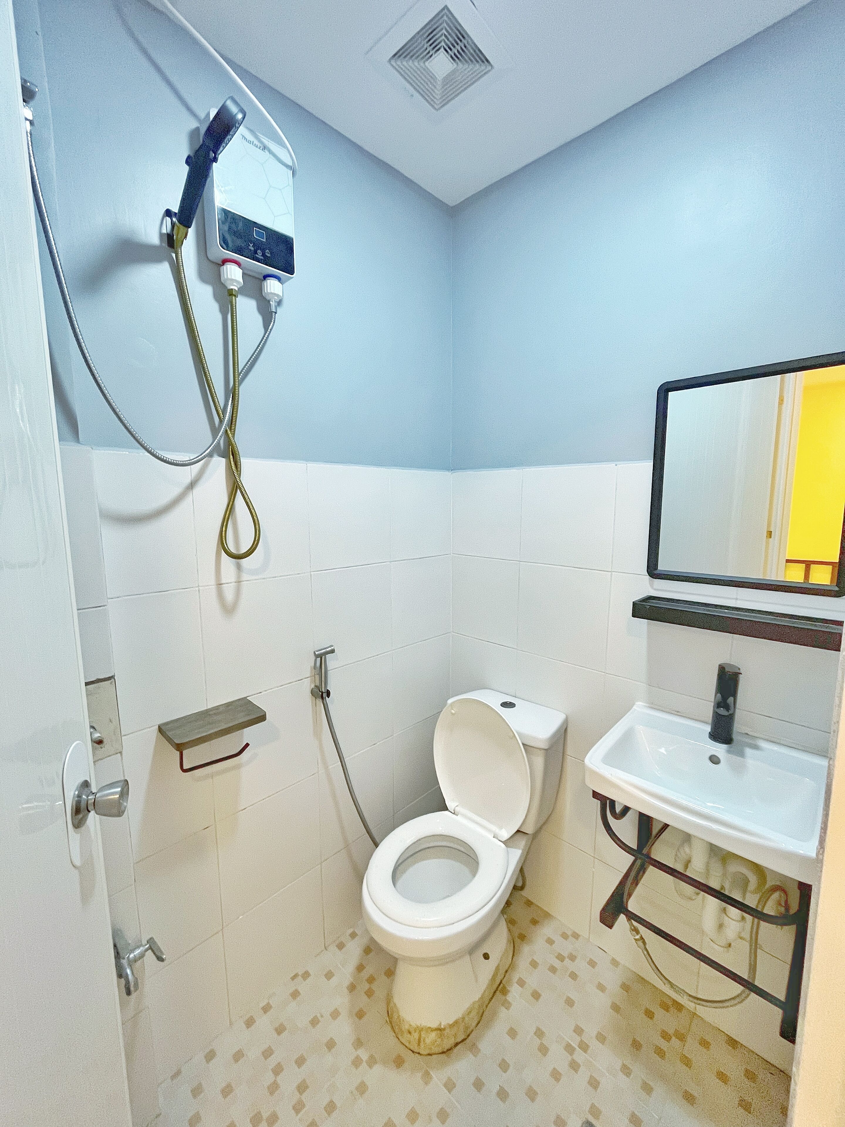 A small bathroom with a toilet, a sink, and a shower unit.