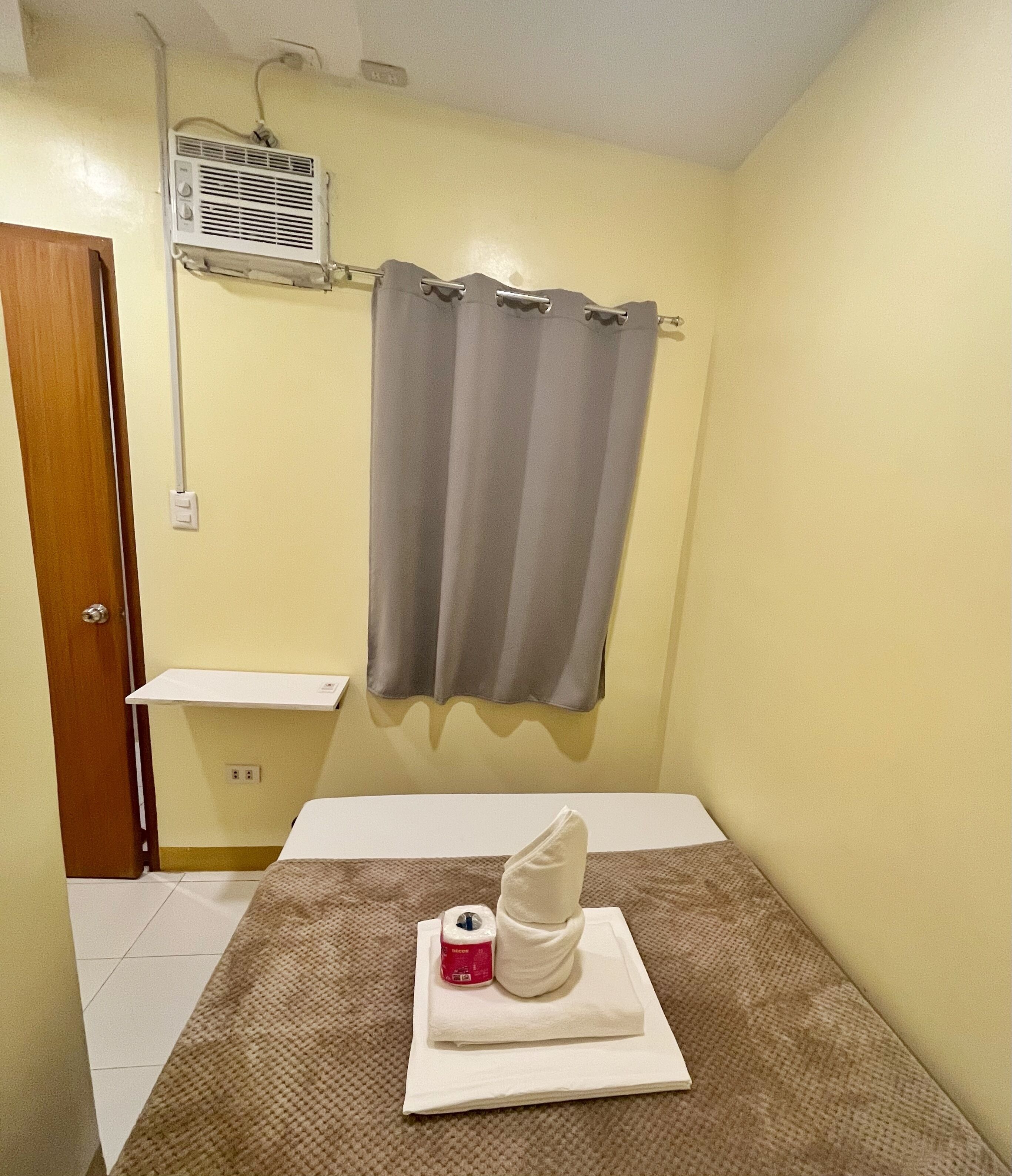 A small, clean bathroom with a toilet, a towel, and a bottle of hand soap on a towel.