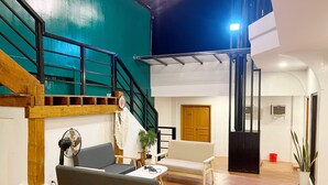 A spacious living area with a wooden staircase, a sofa, a coffee table, and a potted plant. - Cozy Coron Inn (Coron)