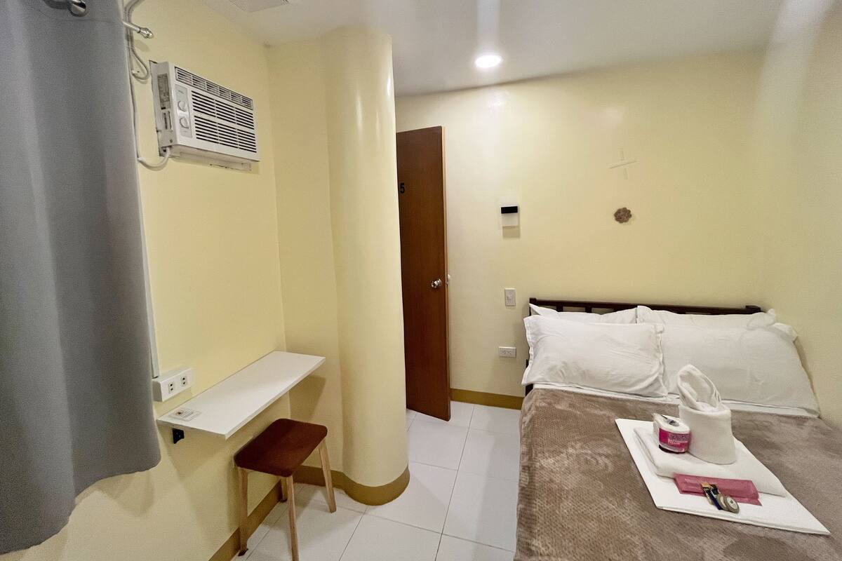 Una habitación de hotel con cama, escritorio, silla y baño con cortina de ducha.