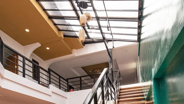 A spacious interior with a wooden staircase, a glass ceiling, and a green wall. - Cozy Coron Inn (Coron)