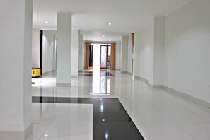 A spacious, modern hotel corridor with a polished floor, large windows, and a view of the outside. - De Nuansa II Dago Syariah by HouseinBandung (Bandung)