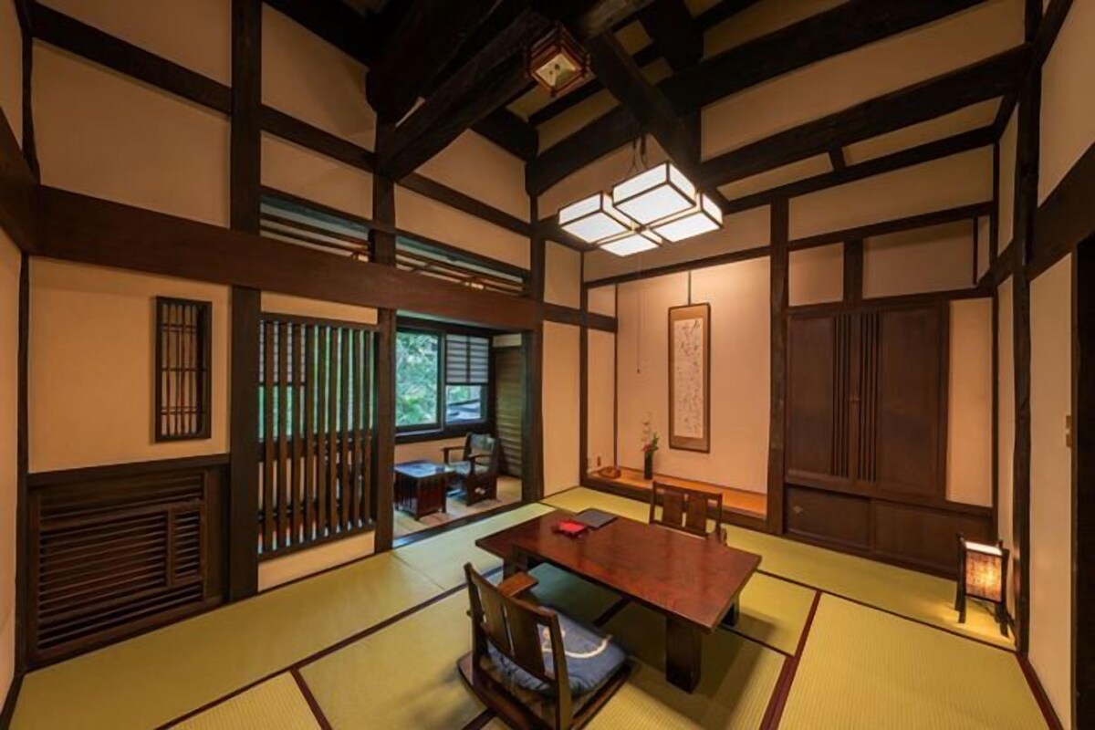 Una habitación japonesa tradicional con suelo de tatami, una mesa de madera baja y puertas correderas.