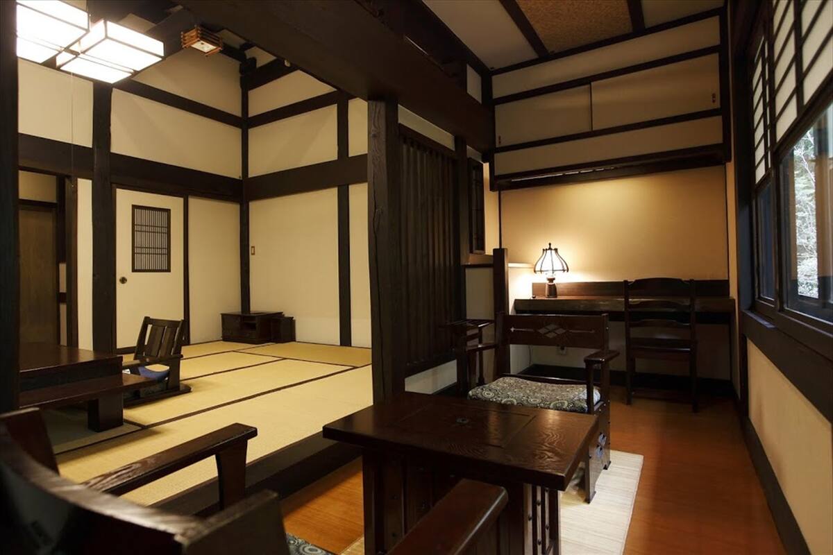 Ein traditioneller japanischer Raum mit Tatami-Bodenbelag, Holzmöbeln und Schiebetüren.