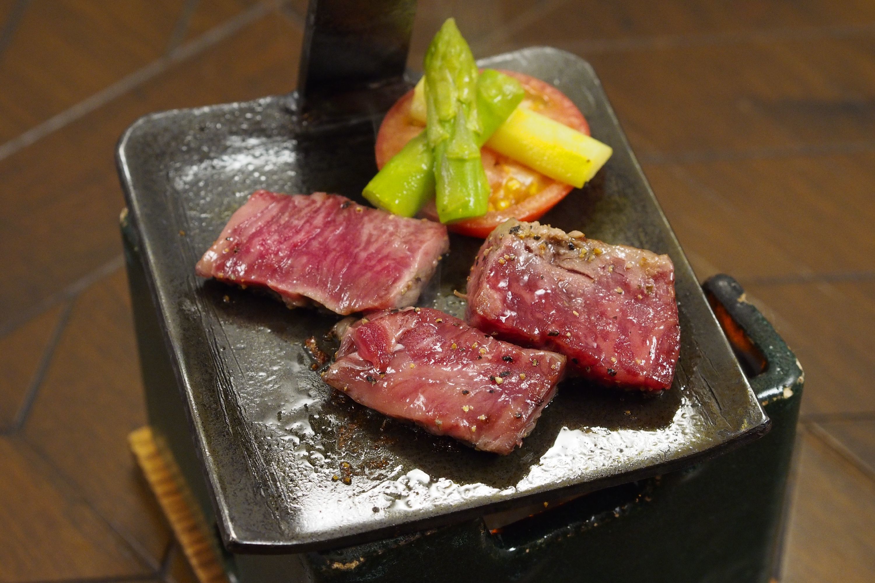 A grill with three pieces of meat and vegetables.