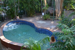 A swimming pool with a tiled edge, surrounded by greenery and a fence. - Frogshollow Backpackers (Darwin)