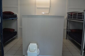 A dormitory room with bunk beds, a white partition, and a white toilet. - Frogshollow Backpackers (Darwin)