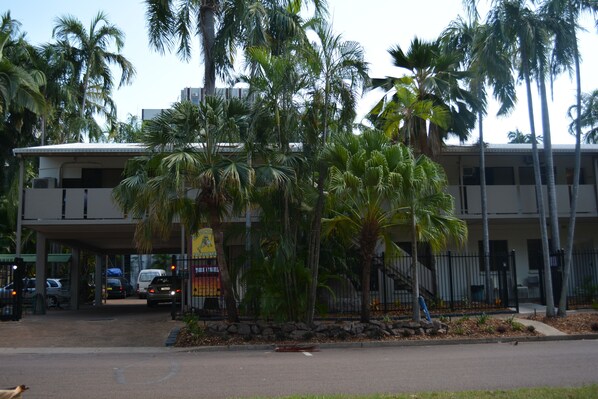 A building with a two-story structure, surrounded by palm trees and a gated entrance. - Frogshollow Backpackers (Darwin)