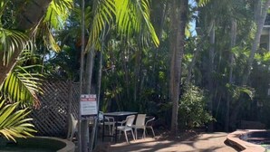 A pool area with a sign, a table, and chairs. - Frogshollow Backpackers (Darwin)