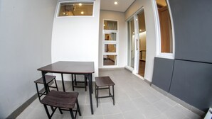 A small, enclosed balcony with a table and chairs, a window, and a door leading to another room. - De Orion Setiabudi Villa (Bandung)