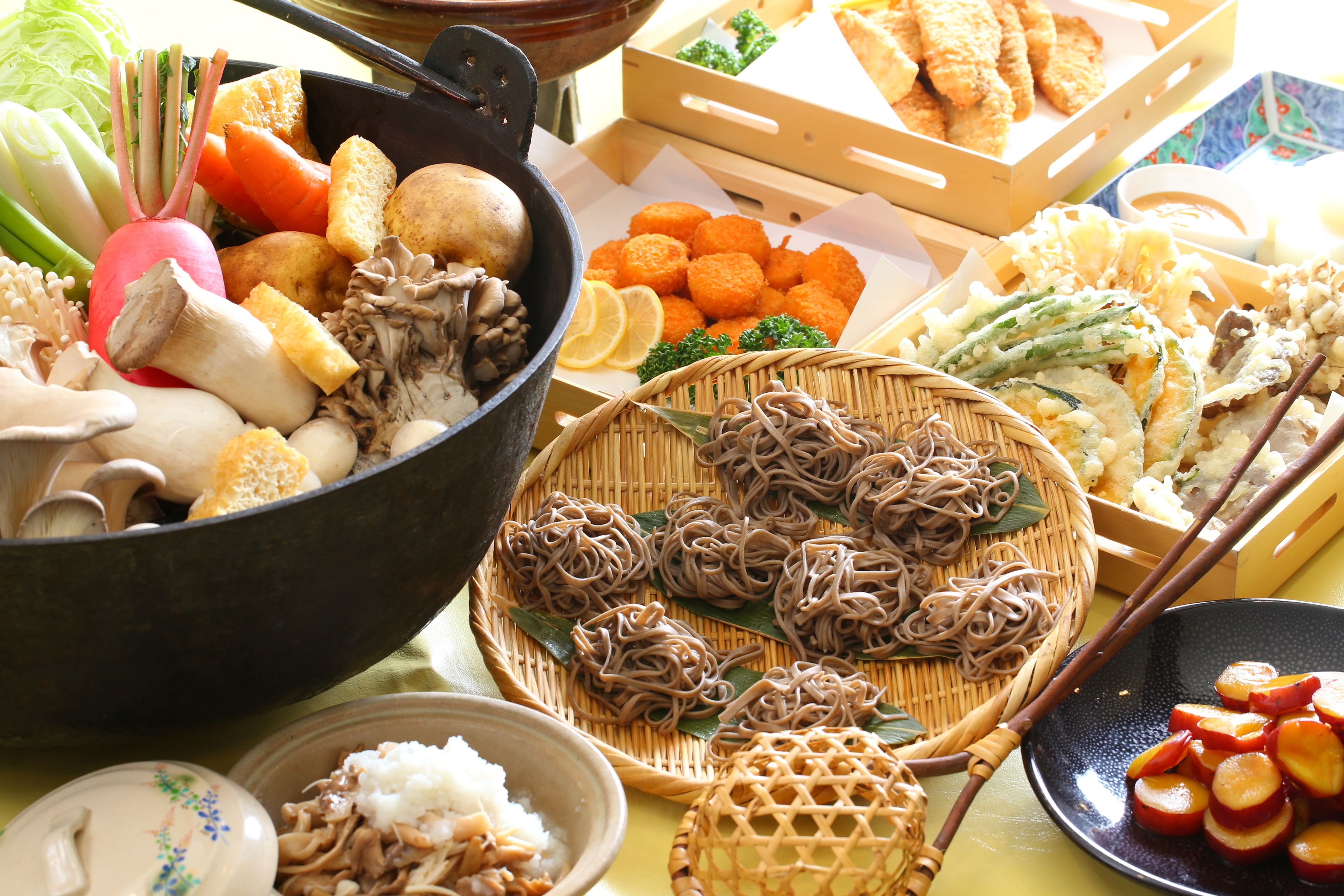 A variety of food items including vegetables, mushrooms, and noodles arranged on a table.