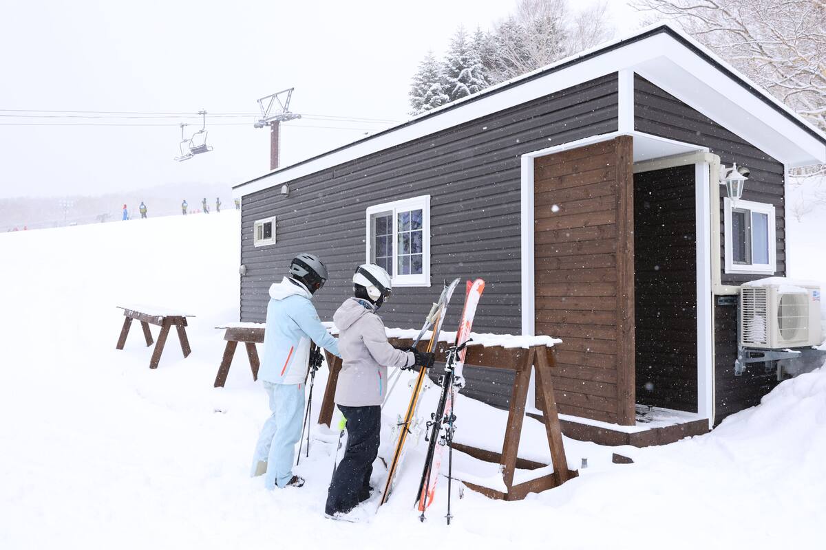 A small cabin with a wooden exterior and a single window, surrounded by snow.