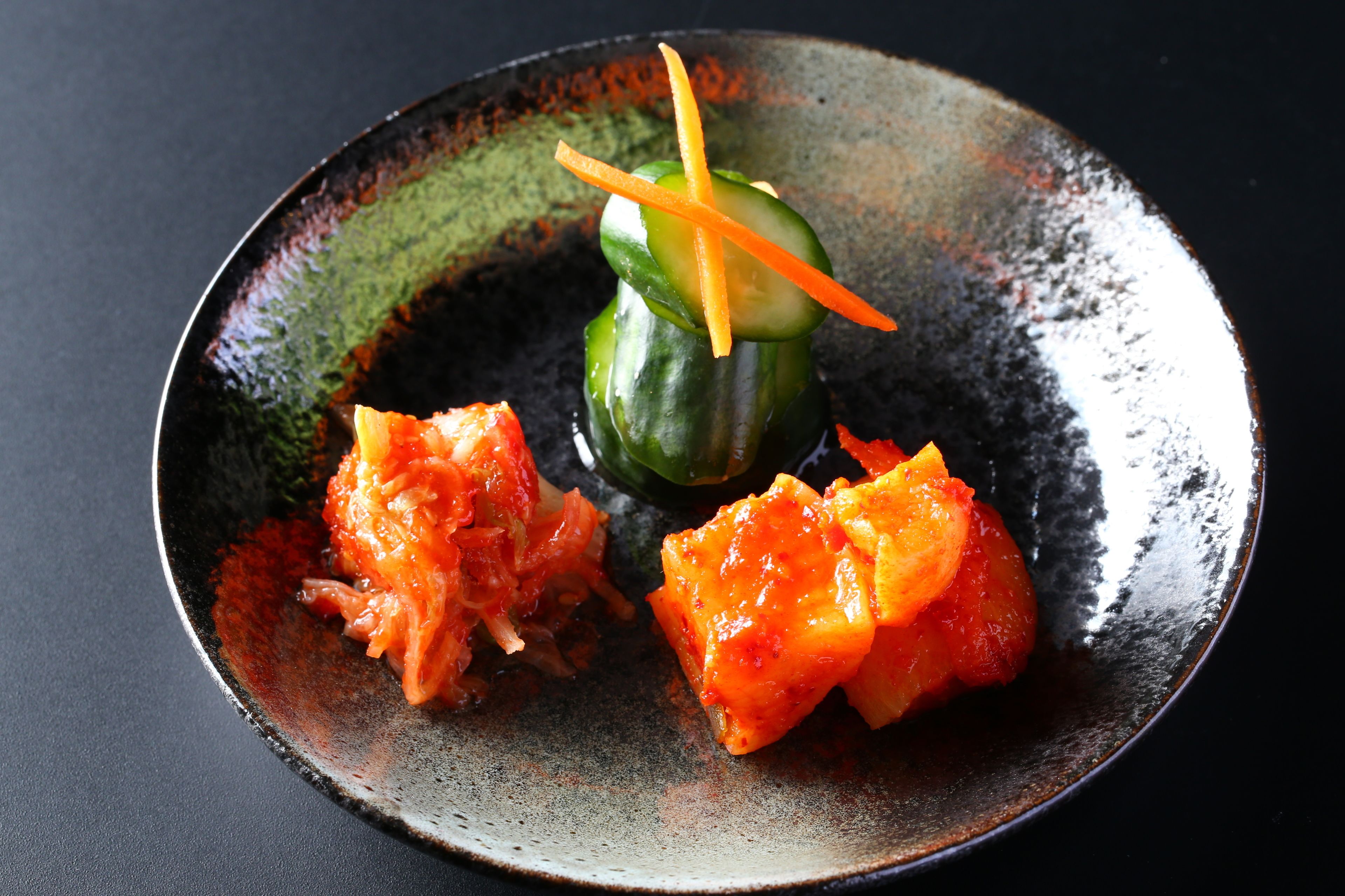 A plate with a green vegetable and two pieces of orange food.