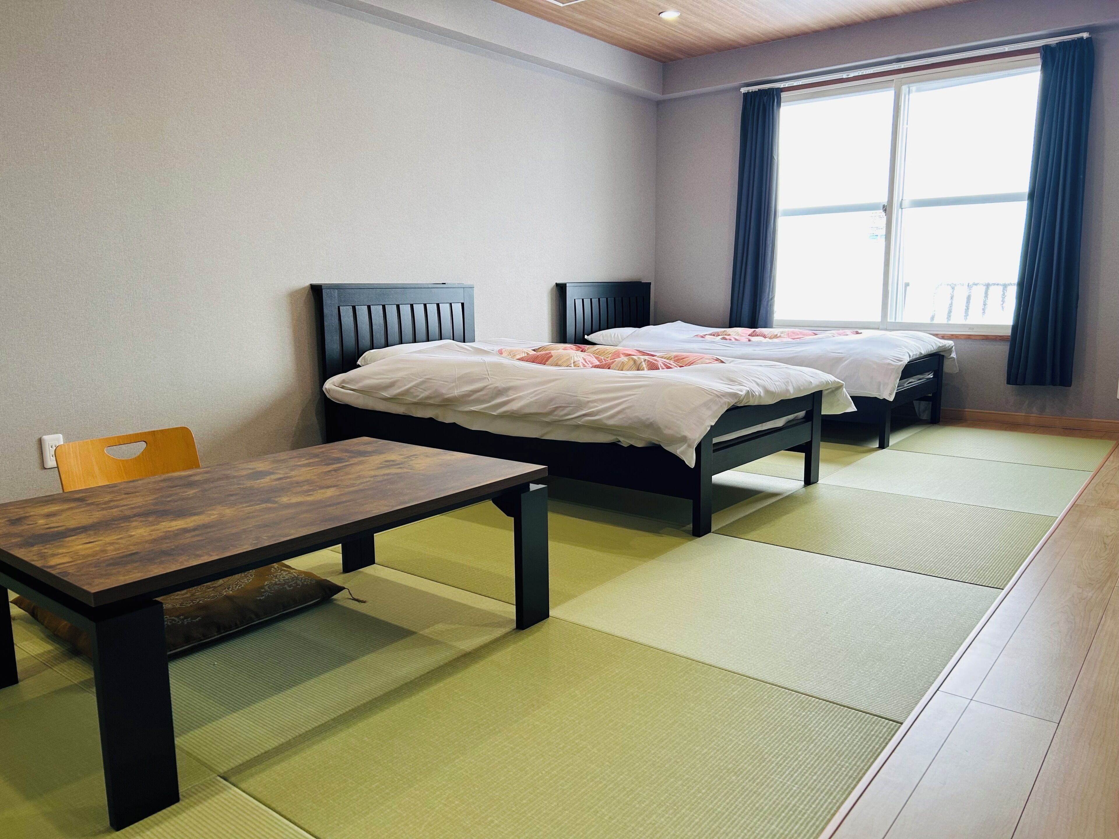 Een kamer met twee bedden, een tafel en een stoel.
