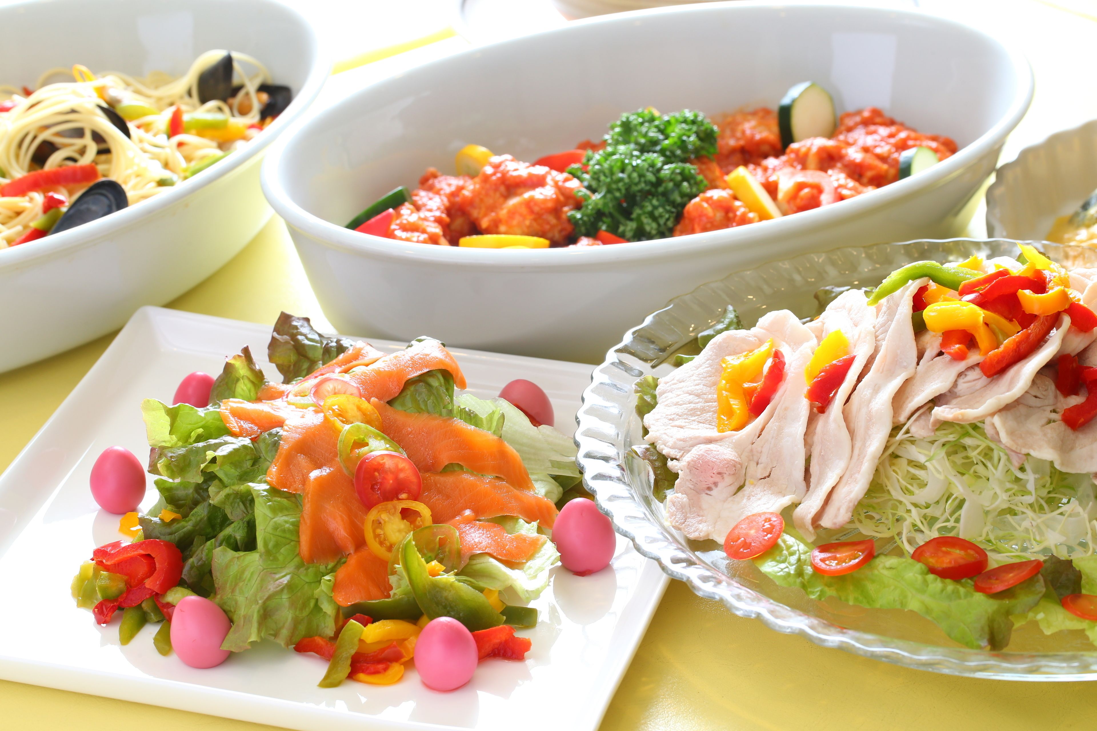 On propose une variété de plats, notamment des pâtes, une salade composée de légumes et de viande, et un plat à base de tomates.
