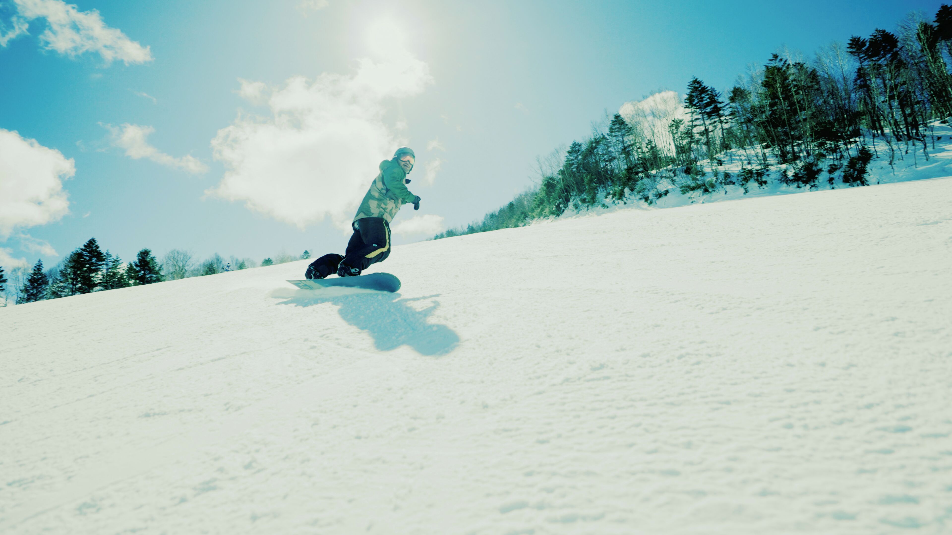 A snowboarder on a snowy slope with trees in the background.