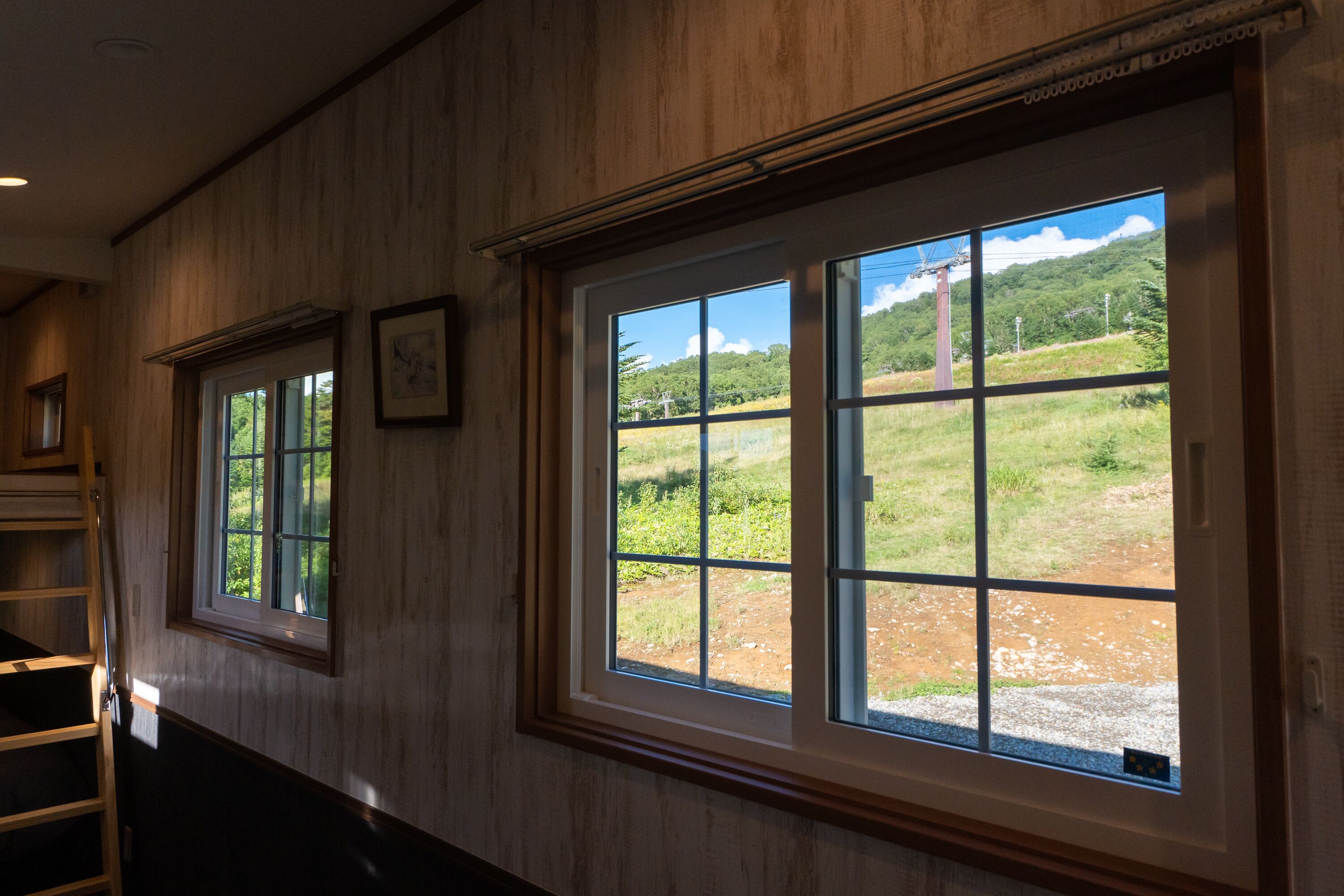 A room with wooden paneling and large windows offering a view of a green landscape.