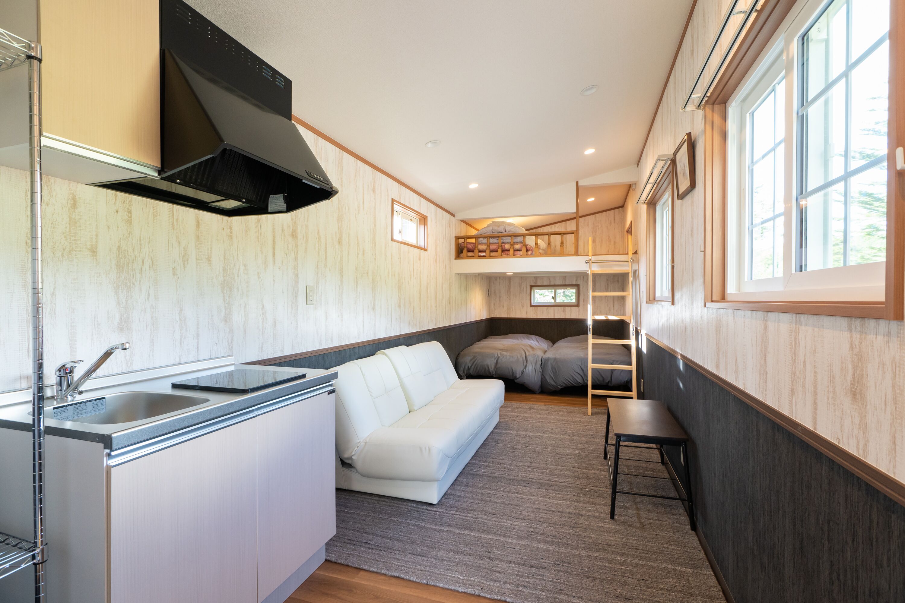 A compact kitchen with a built-in stove, a white sofa, and a small dining table.