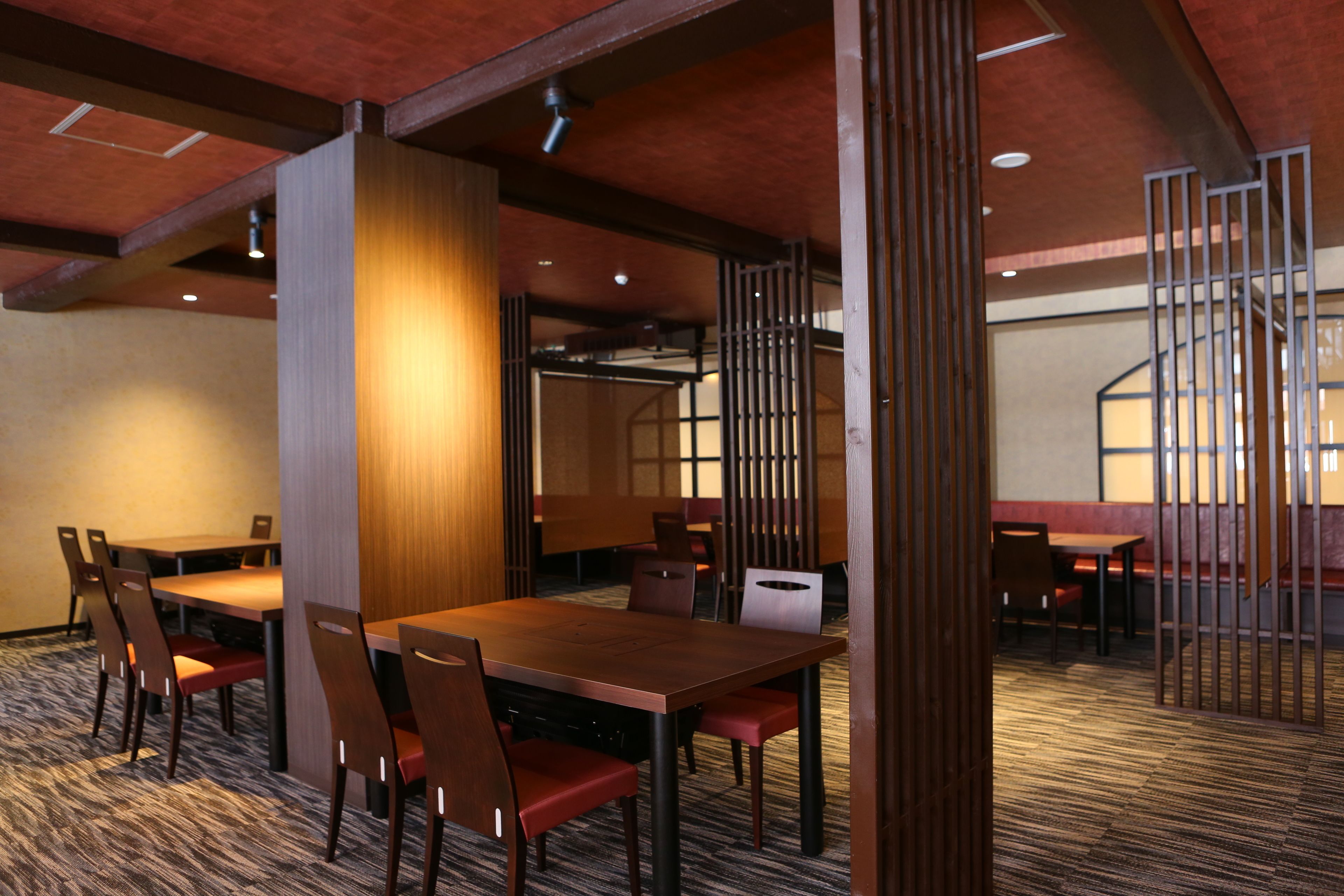 A hotel room with a wooden dining table, chairs, and a carpeted floor.