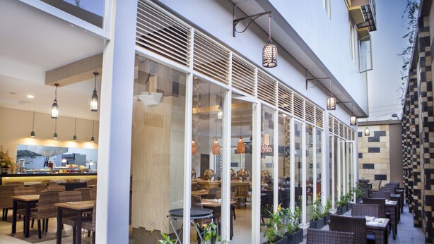 An indoor dining area with tables and chairs, large windows, and hanging pendant lights.