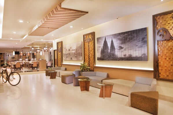 A modern lobby with seating areas, a bicycle, and artwork on the walls. - LAMORA Sagan Yogyakarta (Yogyakarta)