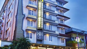 A multi-story hotel with a prominent vertical sign, balconies, and a well-lit entrance.