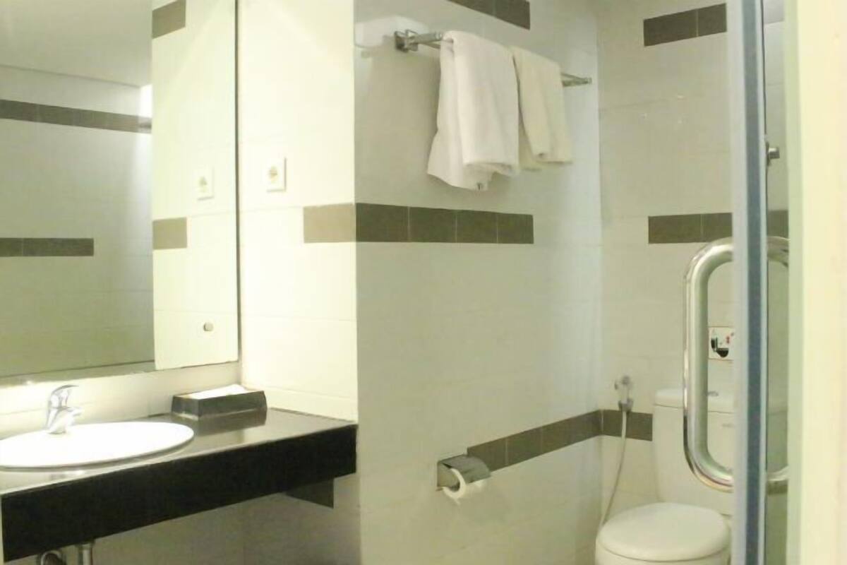 Bathroom features a sink, toilet, and shower area with a glass door.